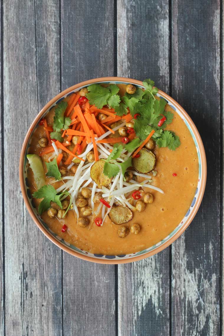 Close up image of vegan curry soup with crispy chickpeas garnished with lime and cilantro.