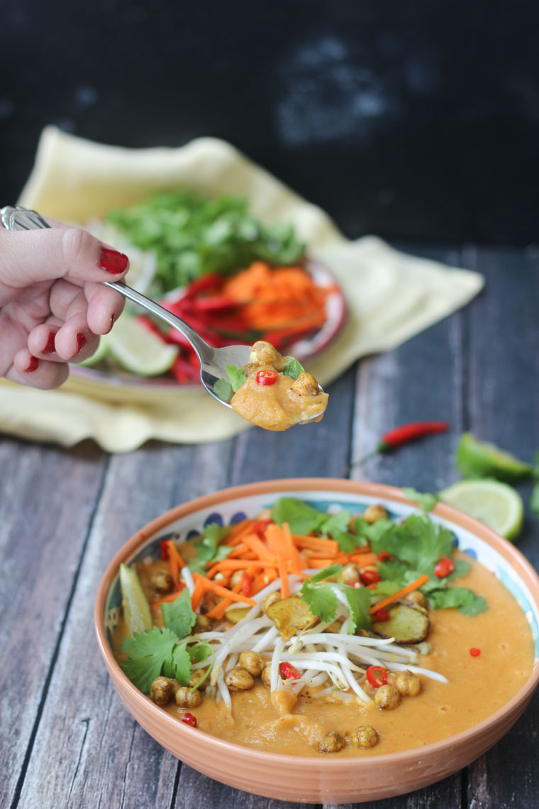 Hand holding a spoon of recipe with sunchokes and chickpeas.