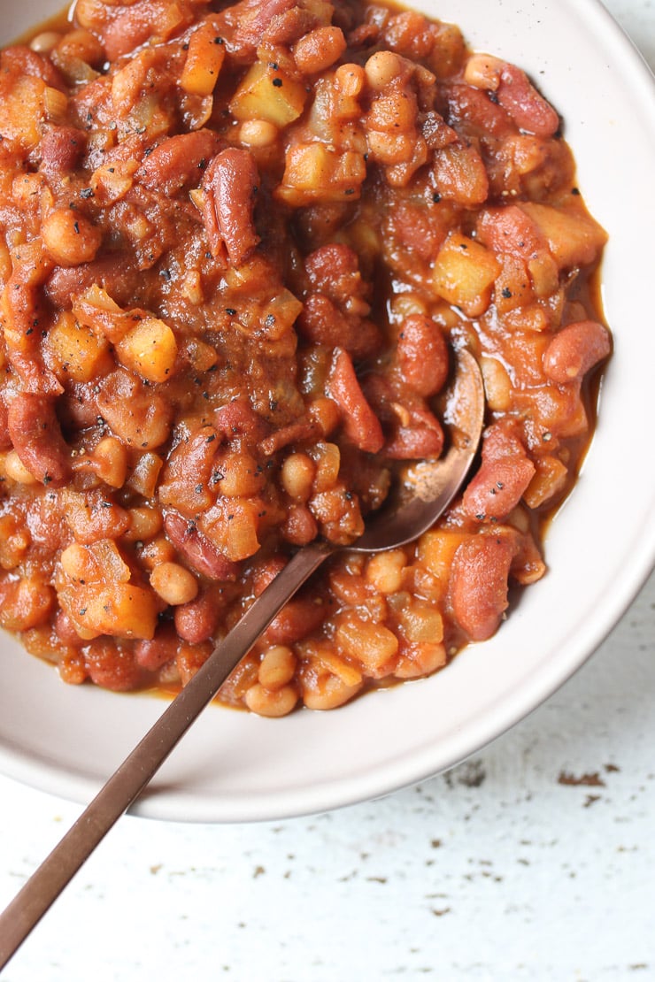Birds eye view of vegan baked beans recipe in a white bowl with a spoon inside. 