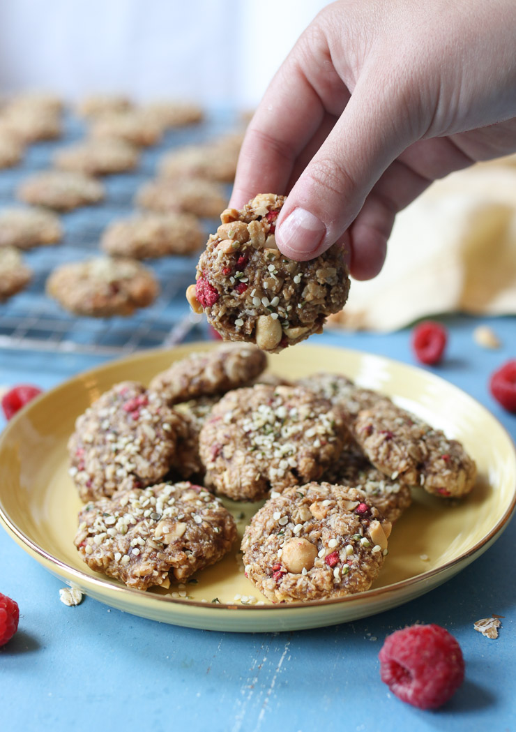 A picture of the peanut butter and jelly cookies on a yellow plate, and a hand holding one cookie.