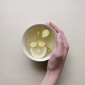 Hand holding mug with water and ginger.