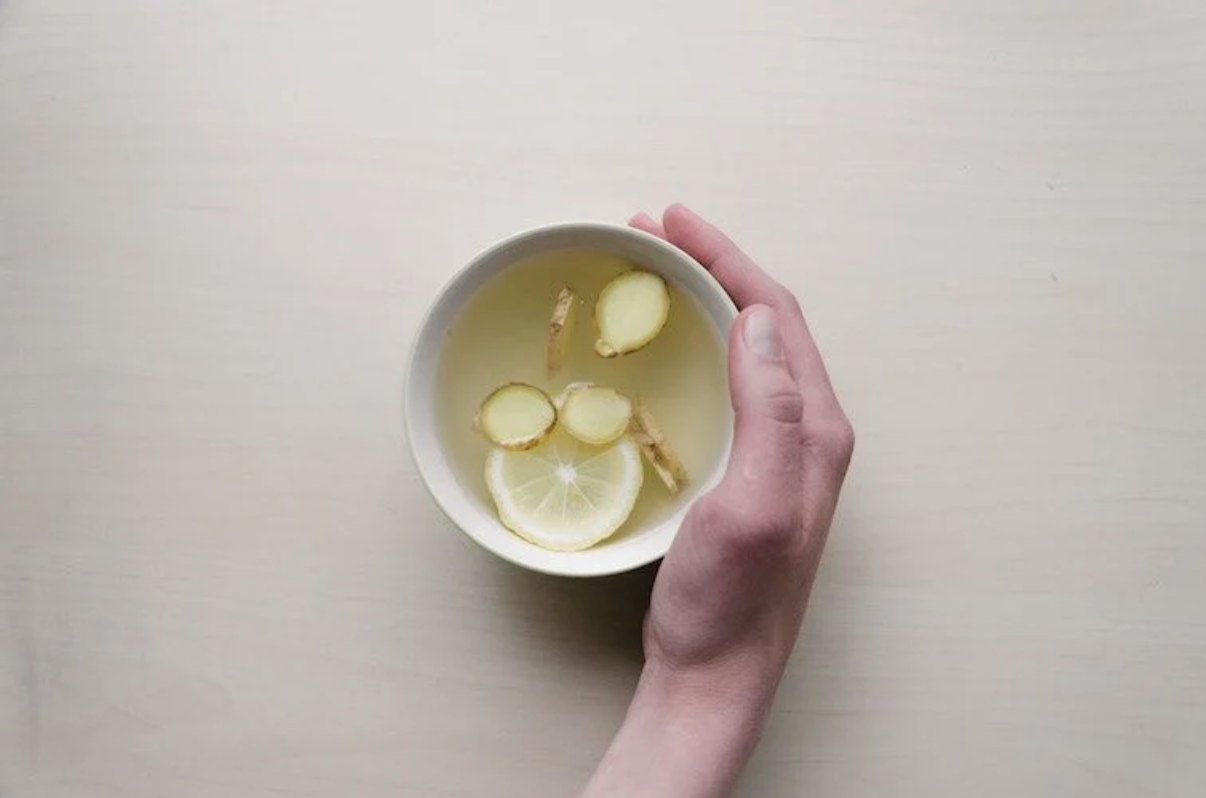 Hand holding a mug with ginger and water.