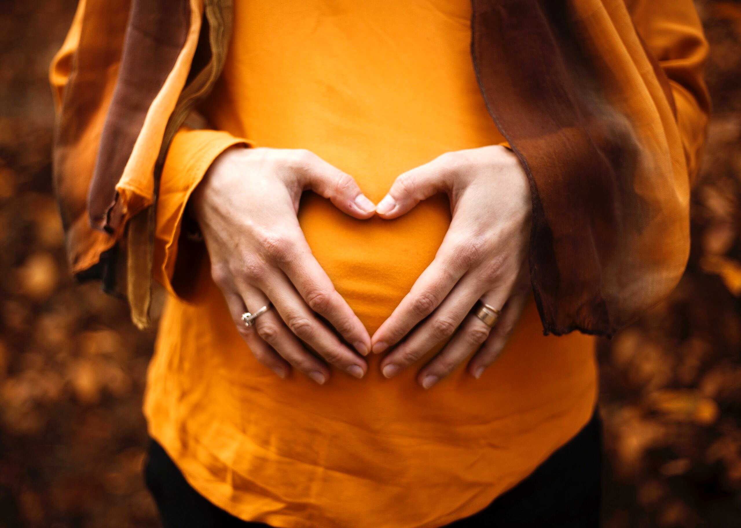 Pregnant person with their hands on their stomach.