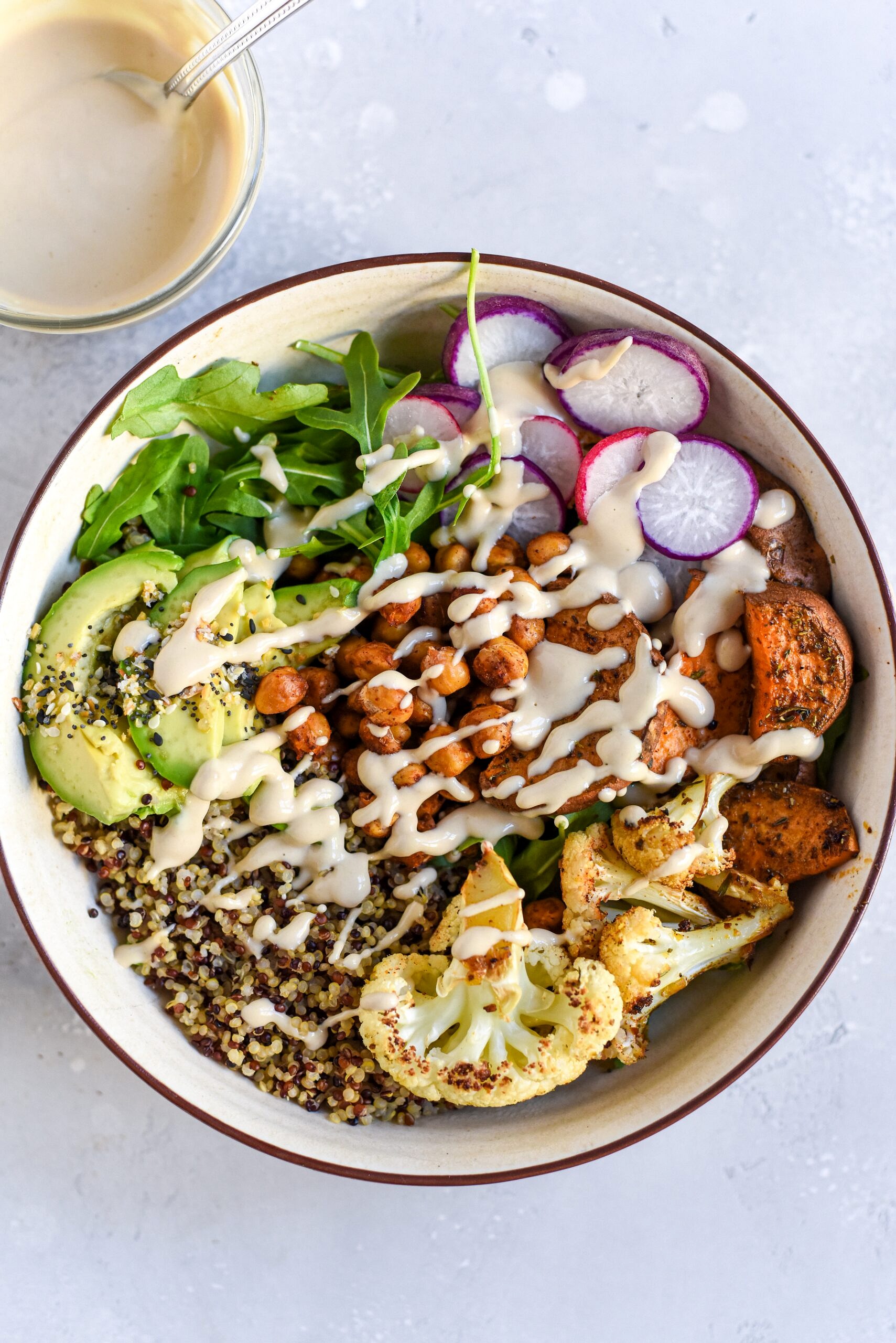 Bowl with vegetables, grains and dressing as a healthy meal option for how to lose baby weight. 