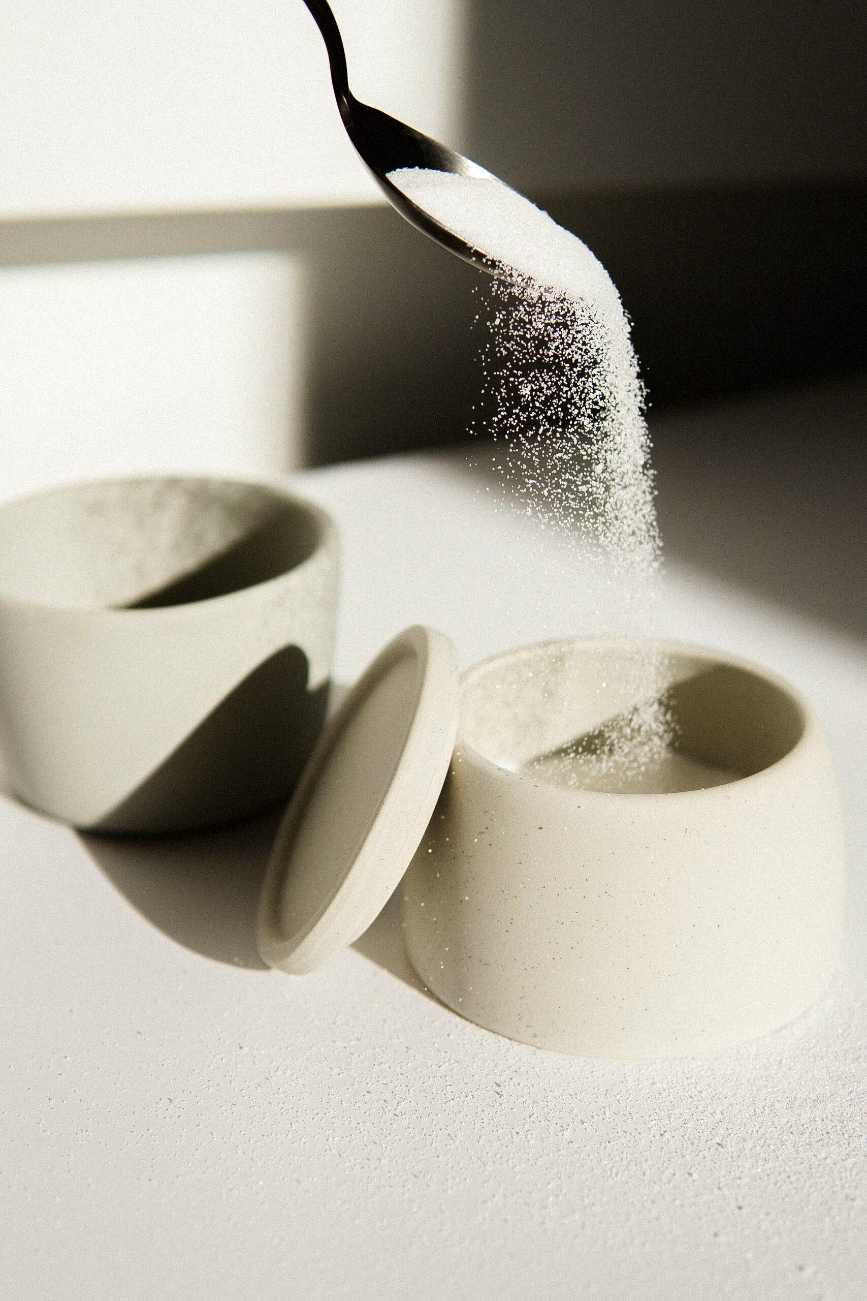 Sugar in being poured into a bowl.