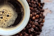 Close up of black coffee with coffee beans in the background.