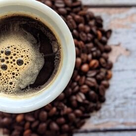Close up of black coffee with coffee beans in the background.