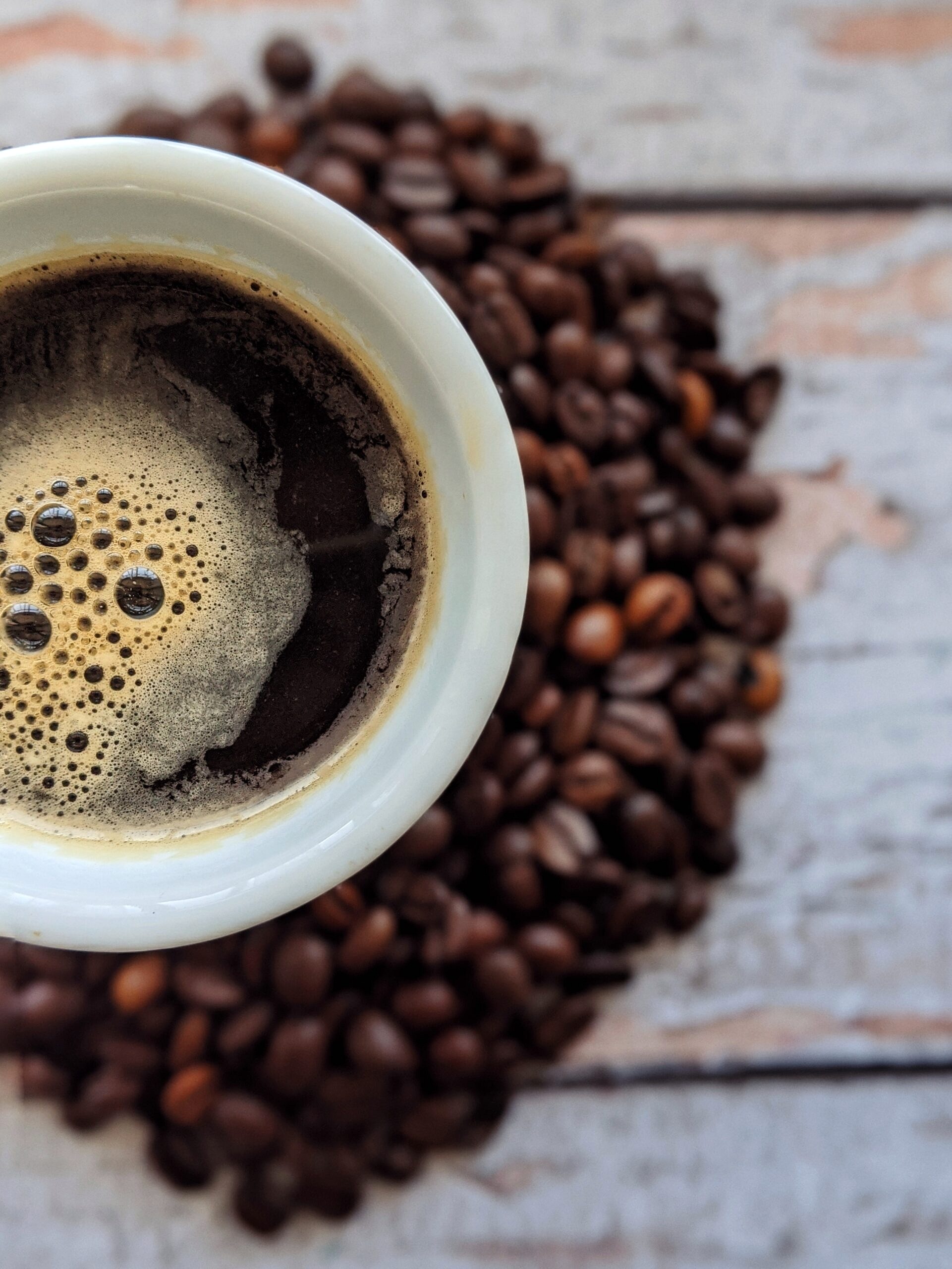 Close up image of black coffee with coffee beans in the background.