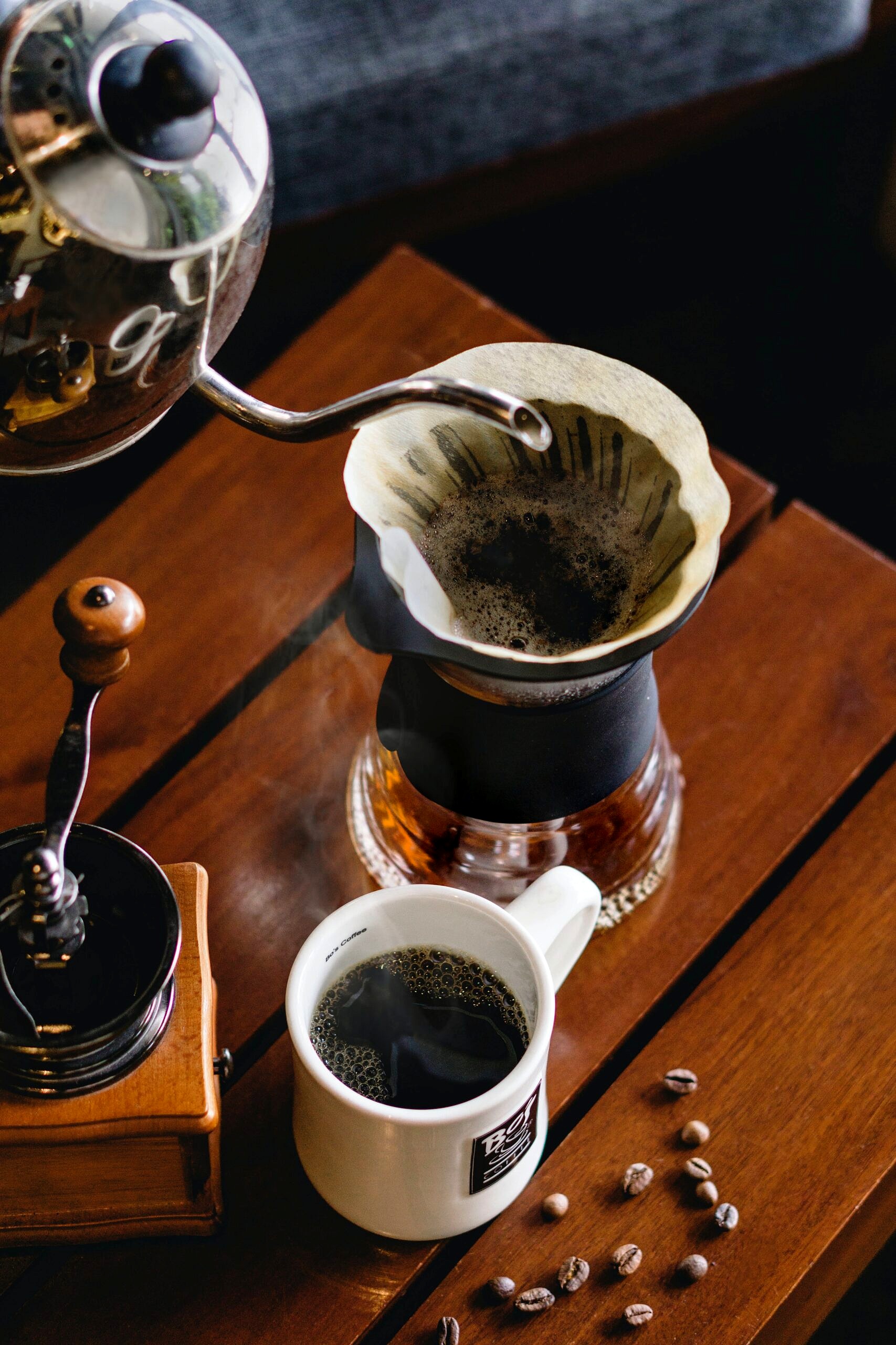 Coffee being poured into a filter next too a coffee cup.