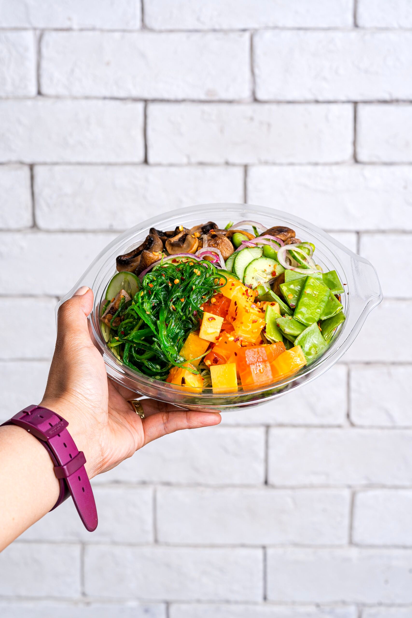 Hand holding a bowl of vegetables.