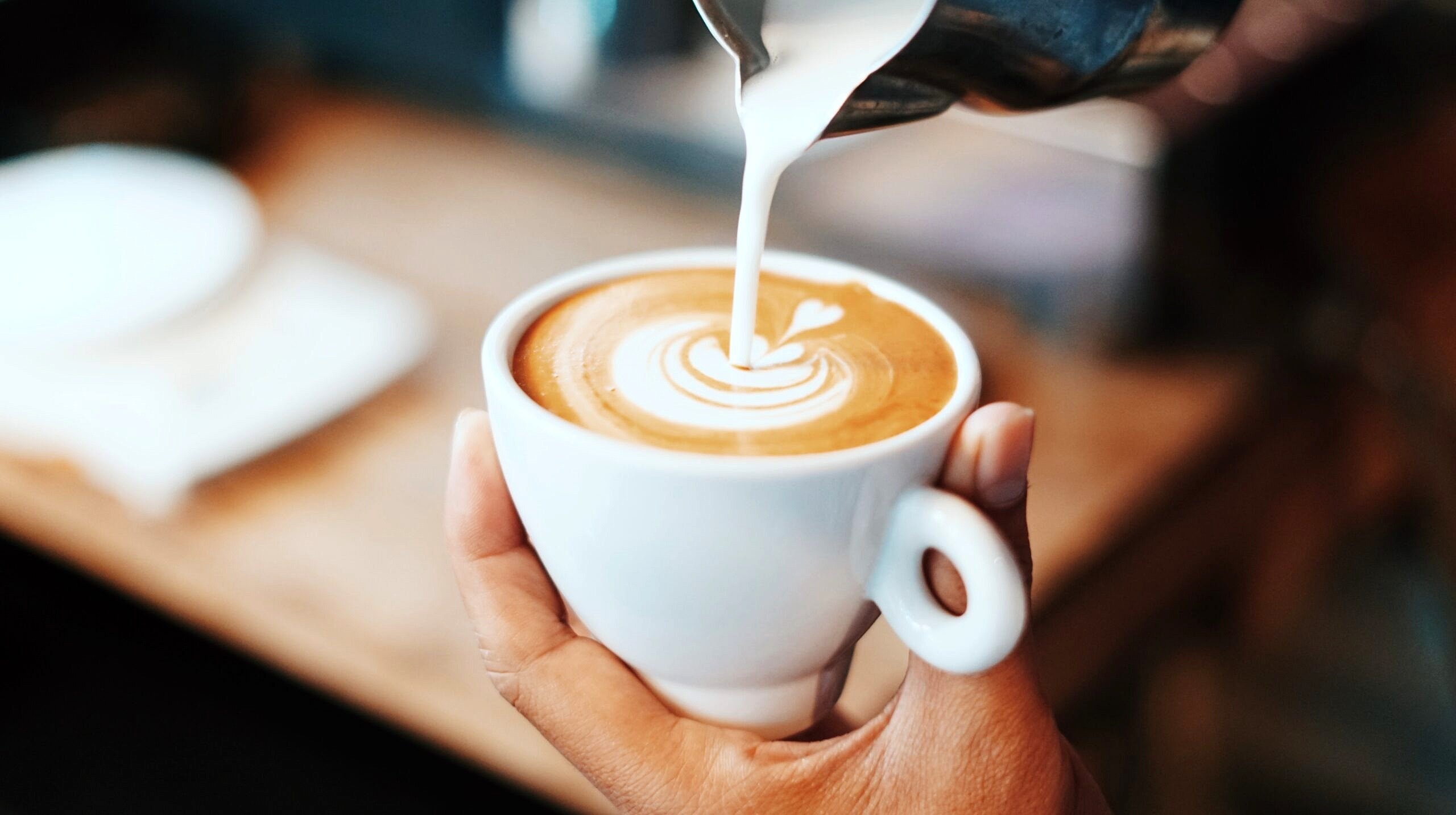 Hands pouring a design into a latte.