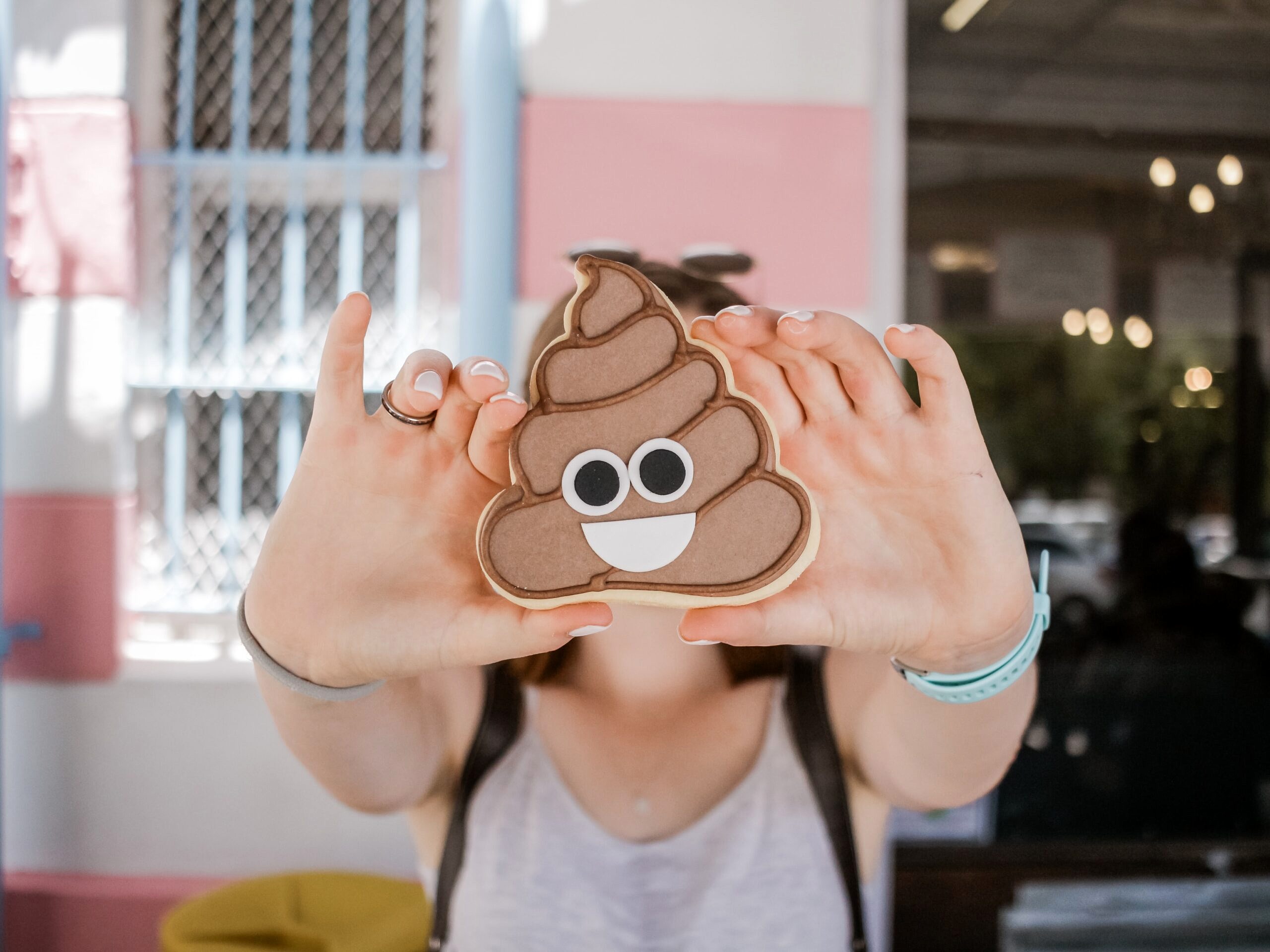 Hands holding a cookie with the poop emoji.