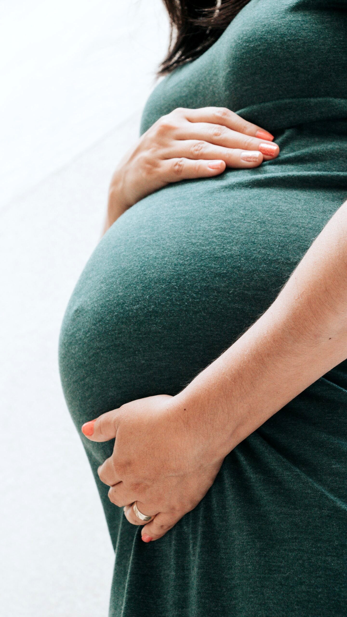 Person holding their pregnant stomach to discuss things to avoid while breastfeeding.