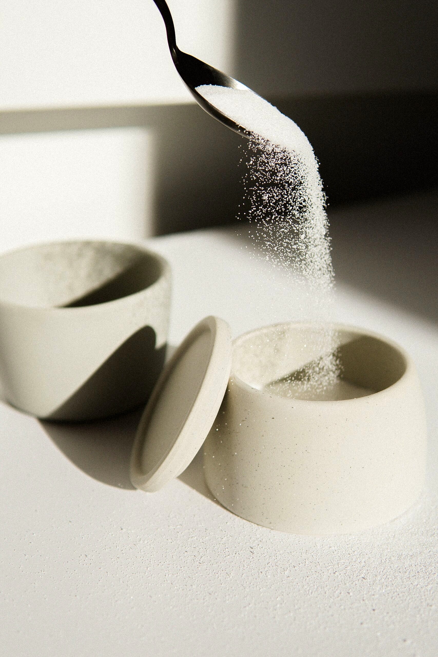 Table sugar being poured into a bowl to represent a common food myth.