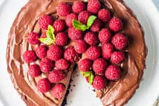 Chocolate cake on a plate with raspberries.