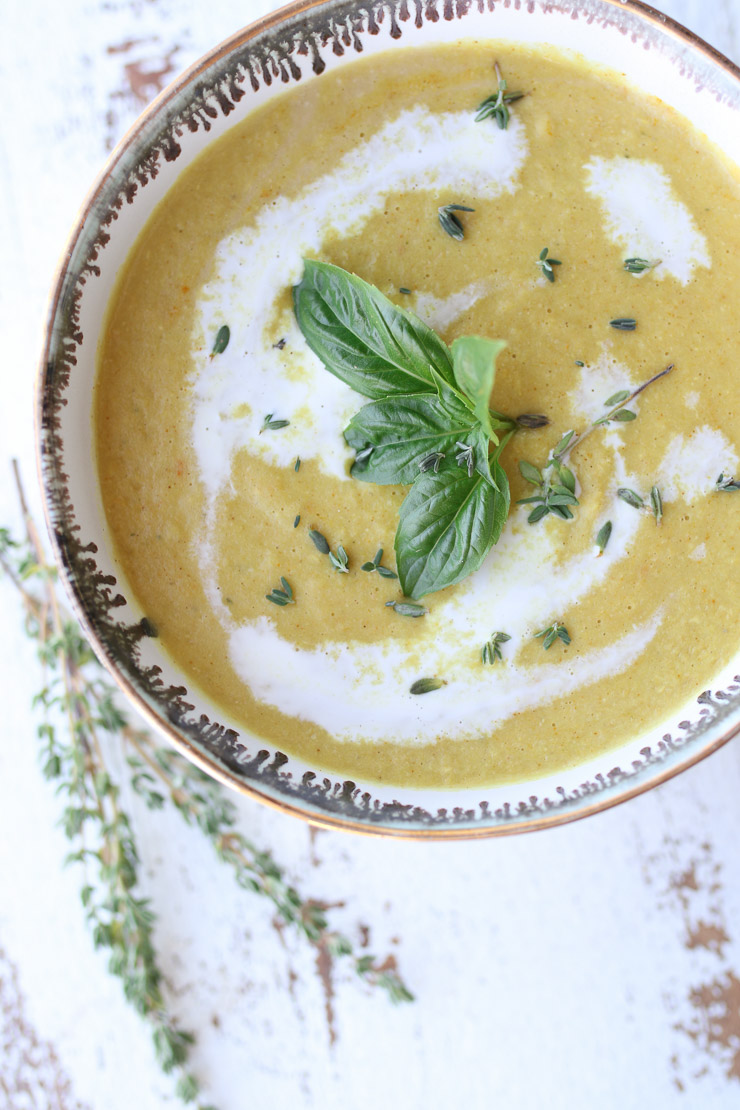 A close up birds eye view of corn soup topped with basil. 