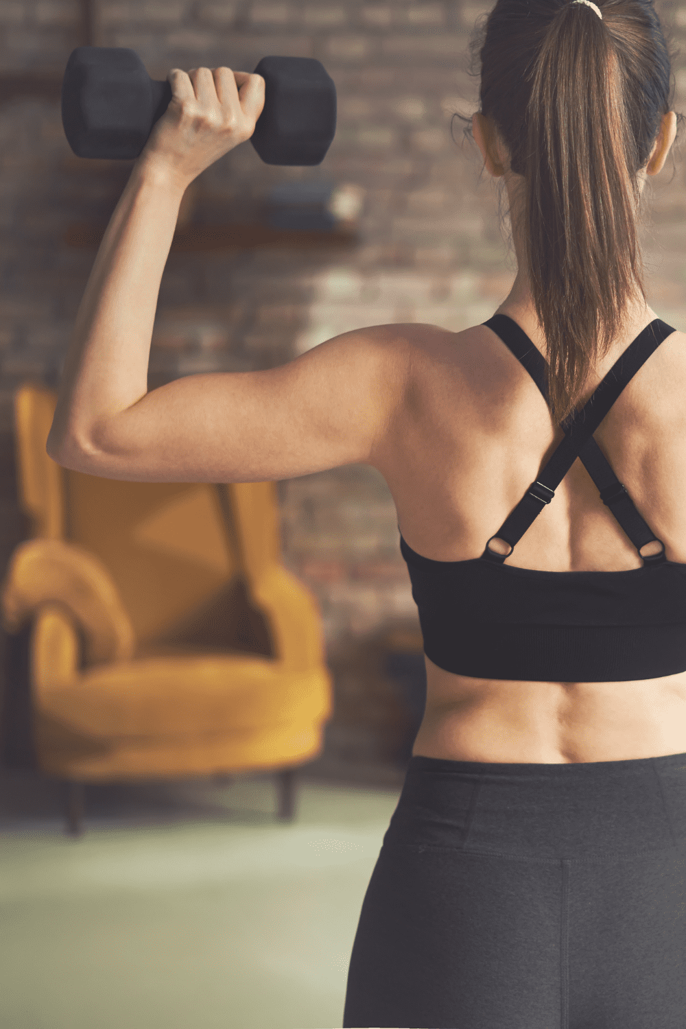 Woman turned around holding a dumbbell. 