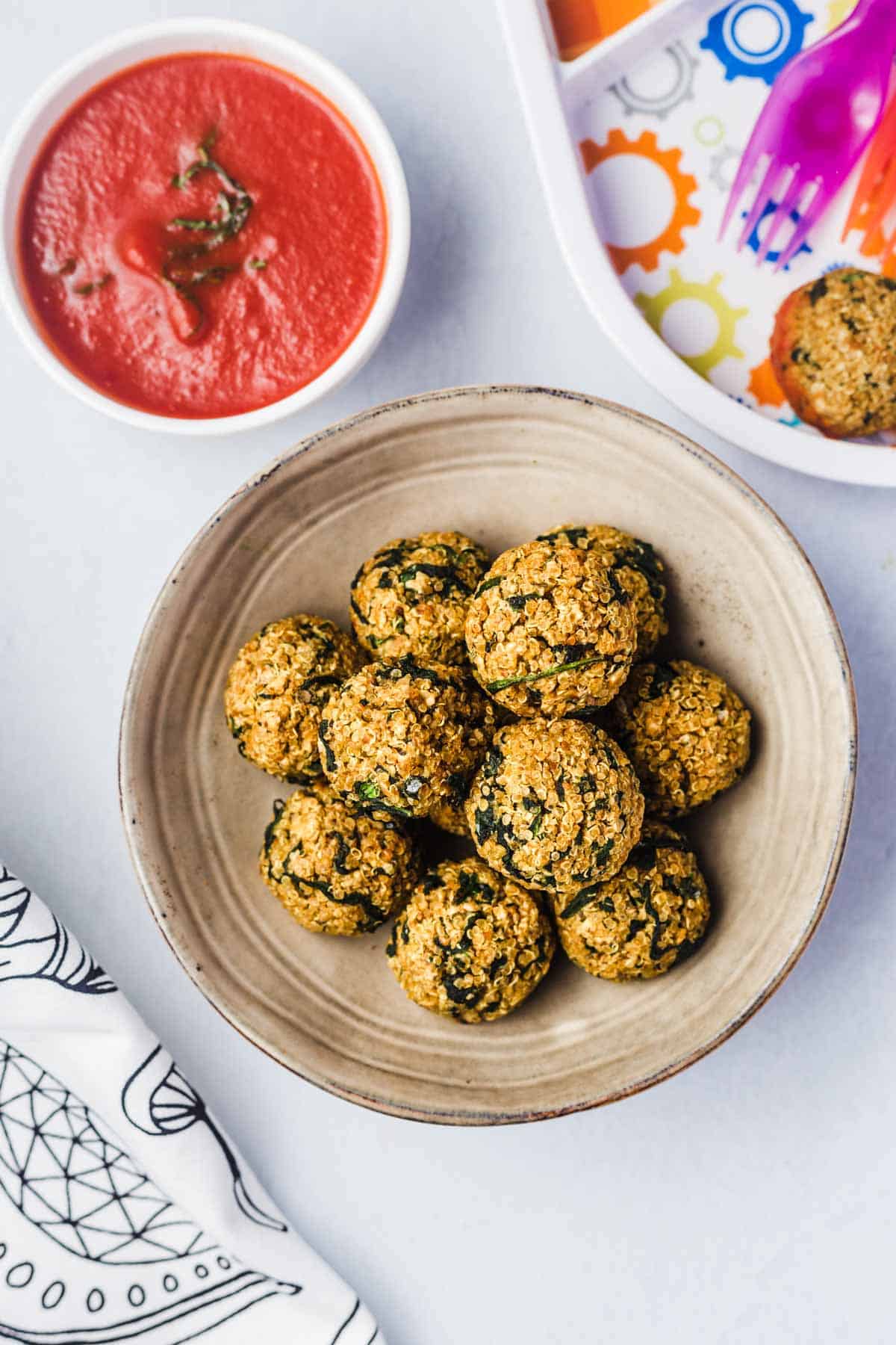 Birds eye view of quinoa balls on a plate, served with marinara sauce.