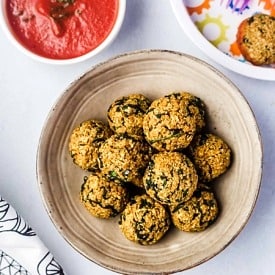 Birds eye view of quinoa balls on a plate, served with marinara sauce.