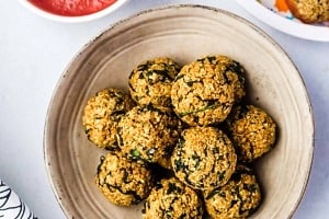 Birds eye view of quinoa balls on a plate, served with marinara sauce.