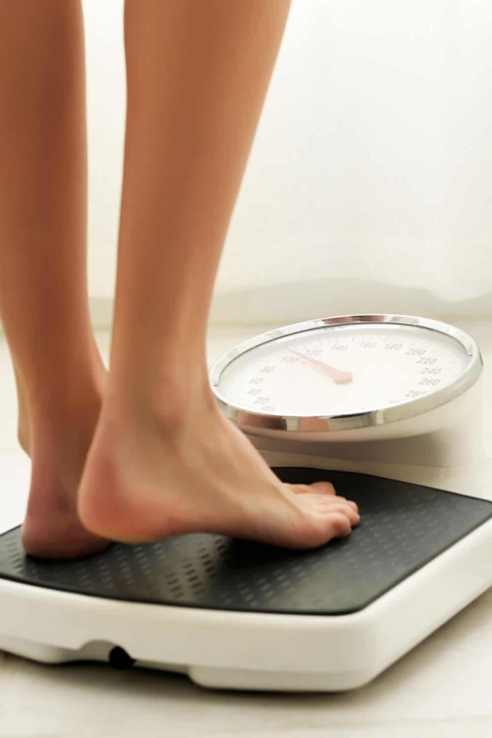 A person standing barefoot on a weight scale. 