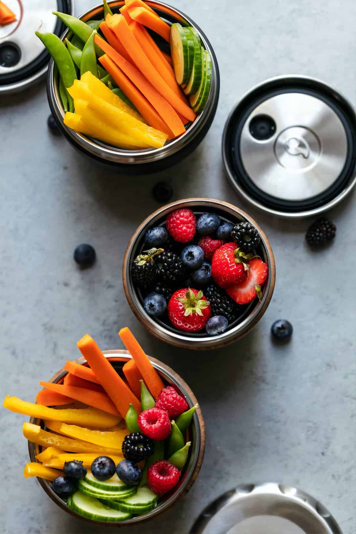 Vegetables and fruits in 3 different canisters from a birds eye view.