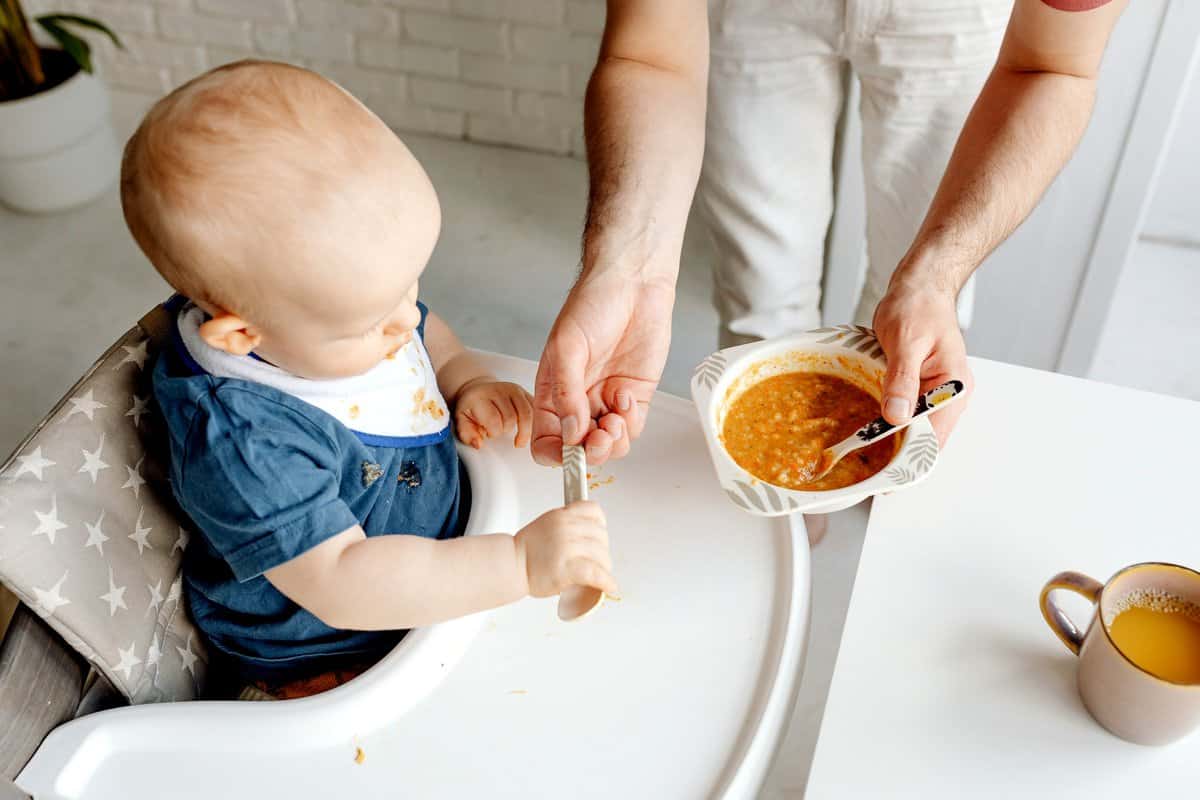 Feeing a baby orange baby food.