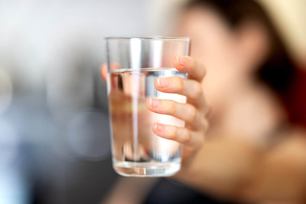 Person holding out a glass of water.