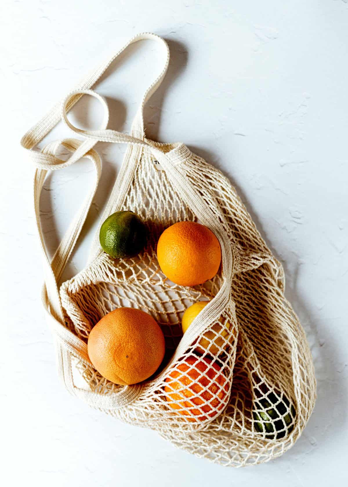 White mesh bag with oranges and fruits.