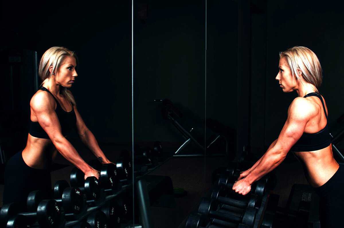 Woman in gym looking at herself in the mirror.