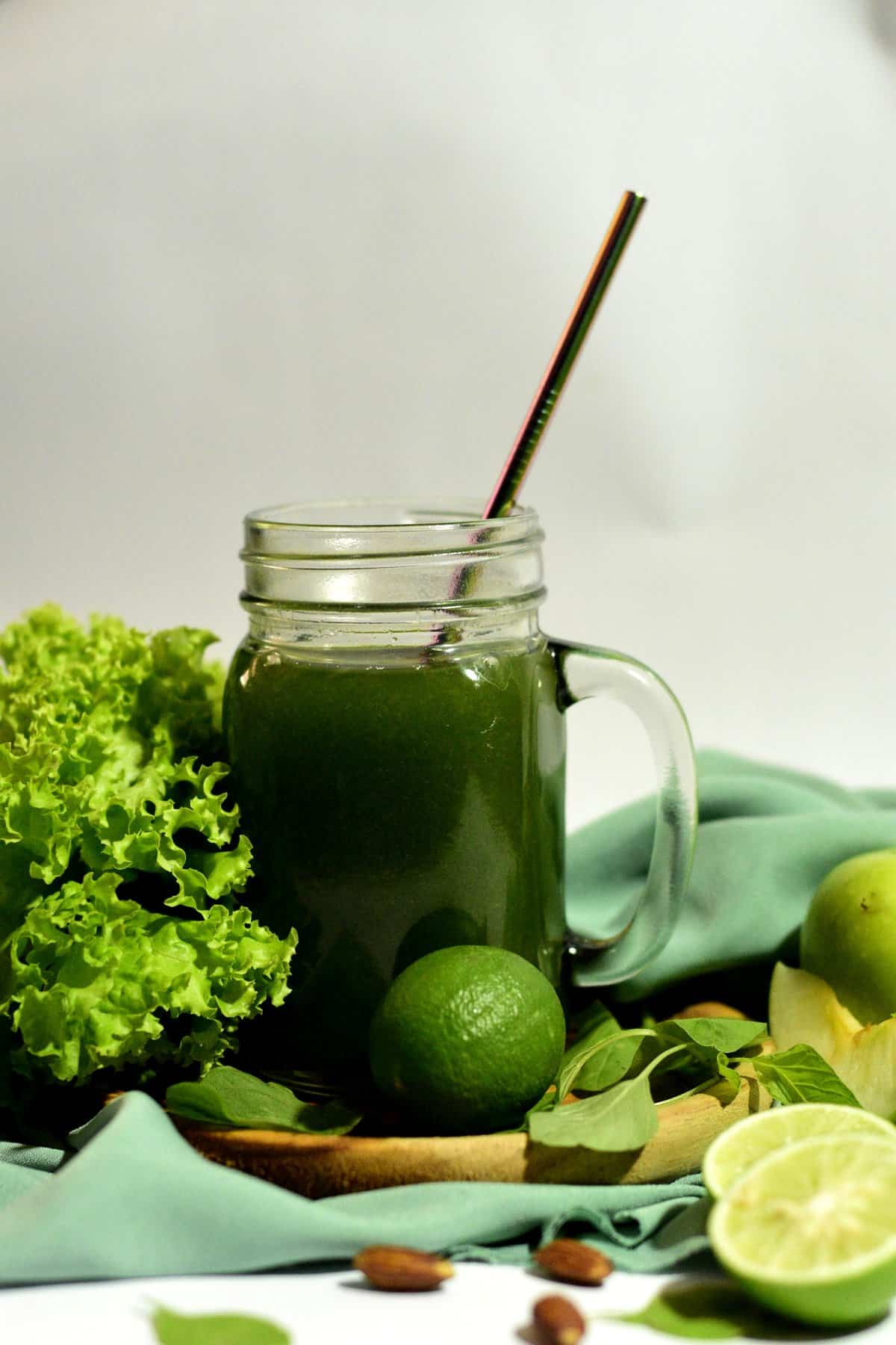 Glass mug of AG1 greens as a health and wellness trend, next to kale, limes and other green produce.