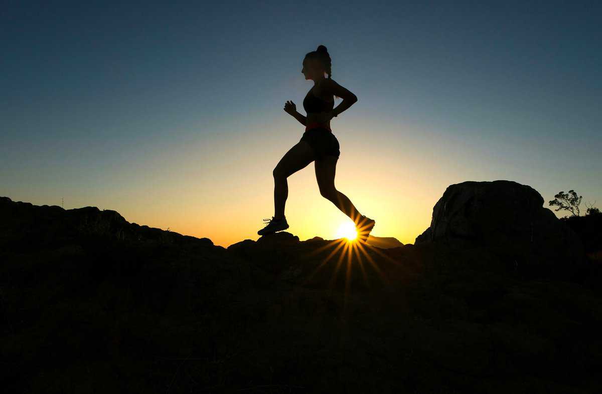 Silhouette of a women running outdoors while the sun is setting.