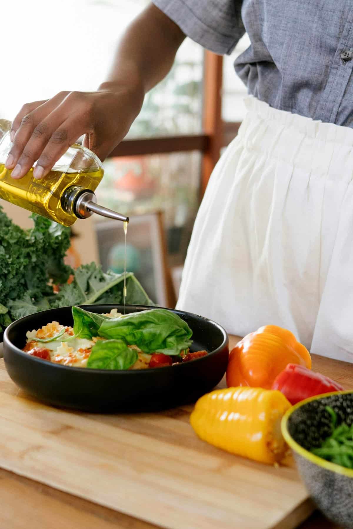 Woman pouring olive oil onto a salad.