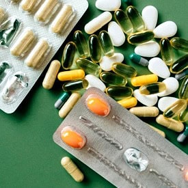 Various dietary supplements scattered against a green background.