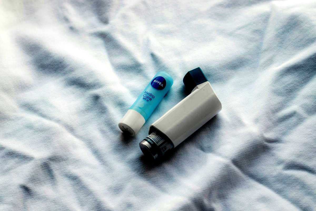 picture of an asthma inhaler and chapstick on a bedsheet