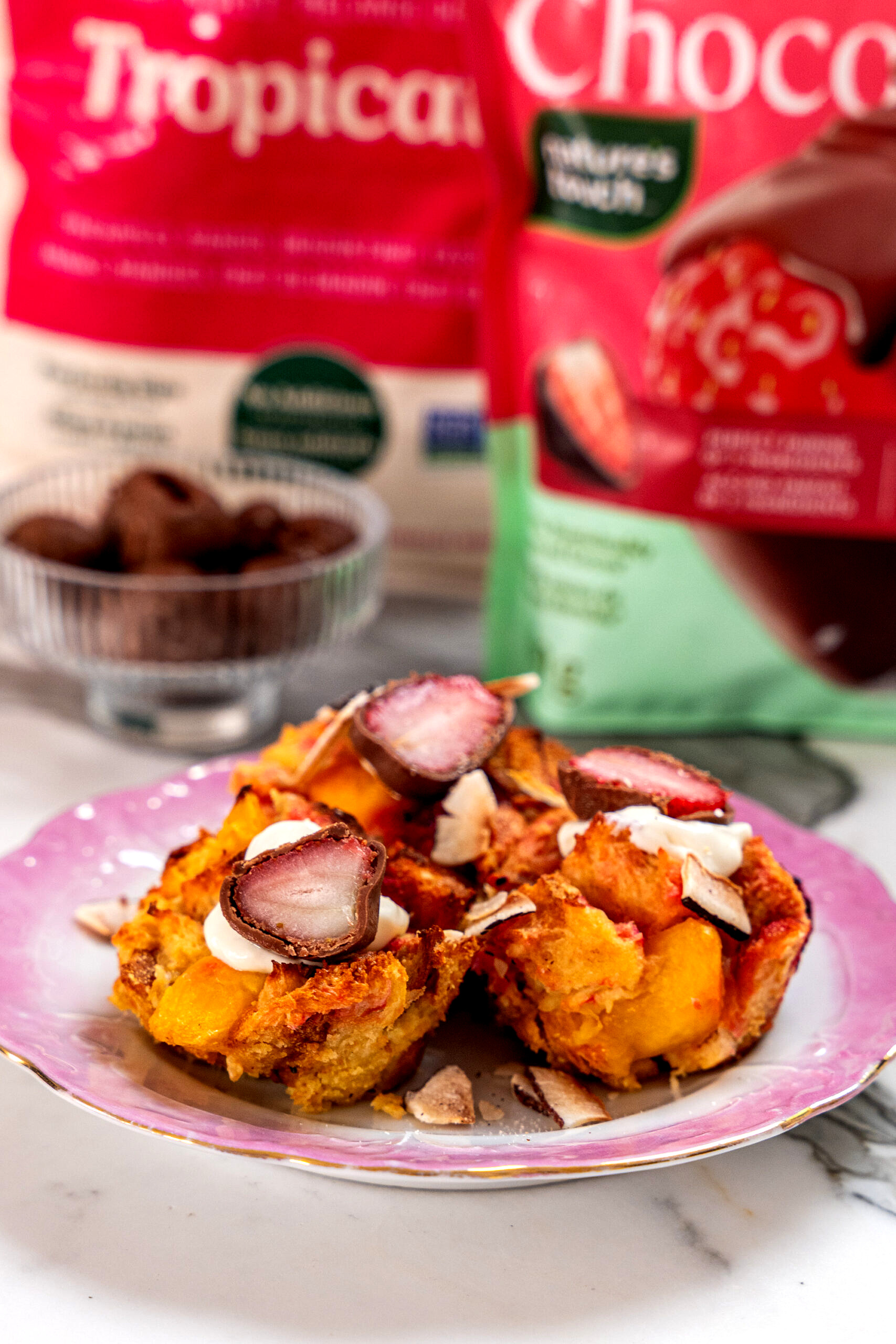 Close up of three tropical french toast muffins, topped with chocolate covered strawberries.