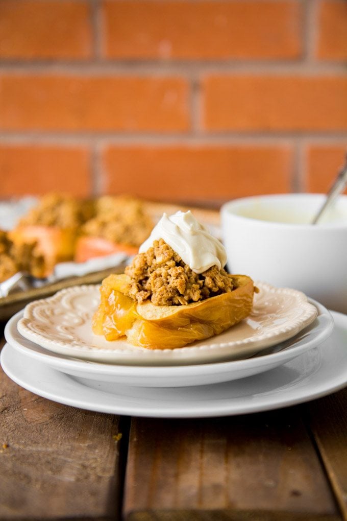 A stack of white plates with an oatmeal cookie granola stuffed baked apple.