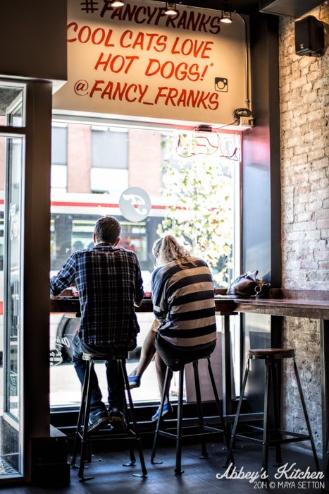 Two people sitting in front of a window, eating.