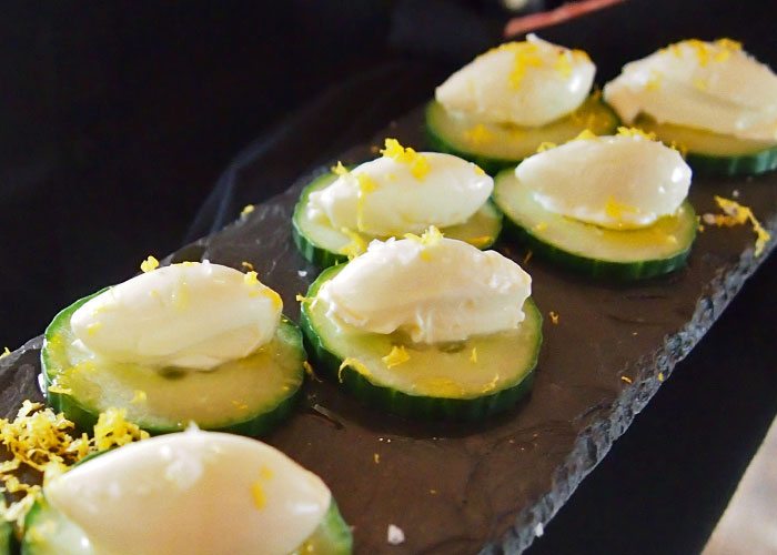 Multiple slices of cucumbers with cheese on top.