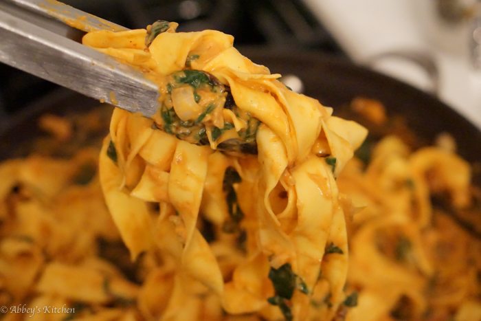 A close up image of a tong lifting up pumpkin chipotle pasta.