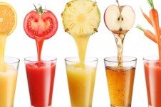 Three glasses of juice with the corresponding produce over top: tomato, pineapple, and apple.
