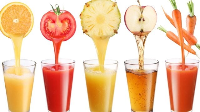 Three glasses of juice with the corresponding produce over top: tomato, pineapple, and apple.