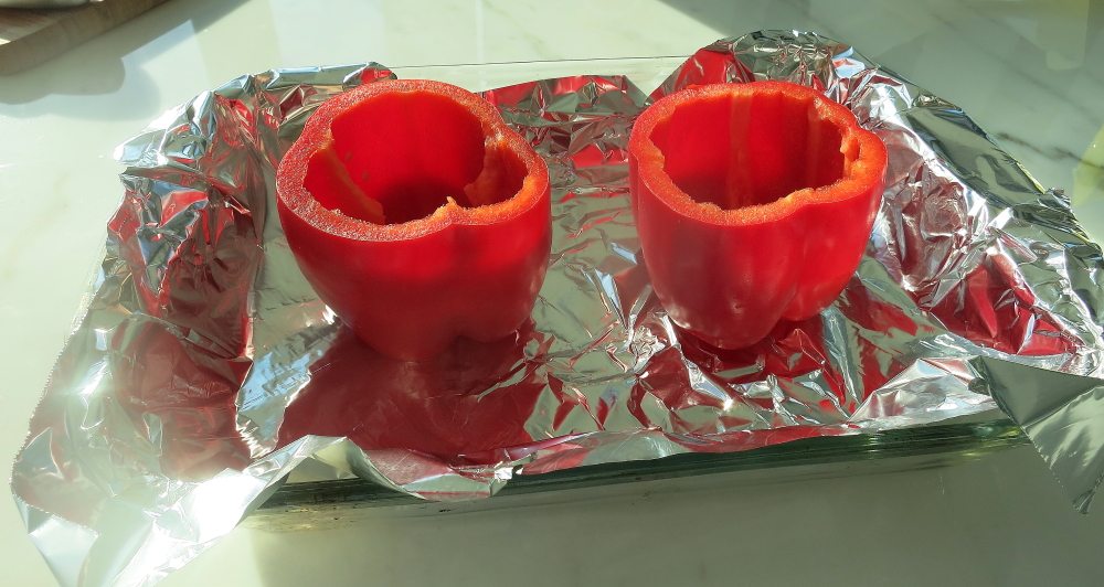 Two red bell peppers with the tops cut off and the seeds removed.