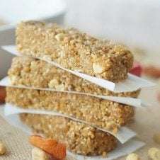 A stack of four gluten free no bake granola bars with peanut butter and apricot with parchment paper in between.