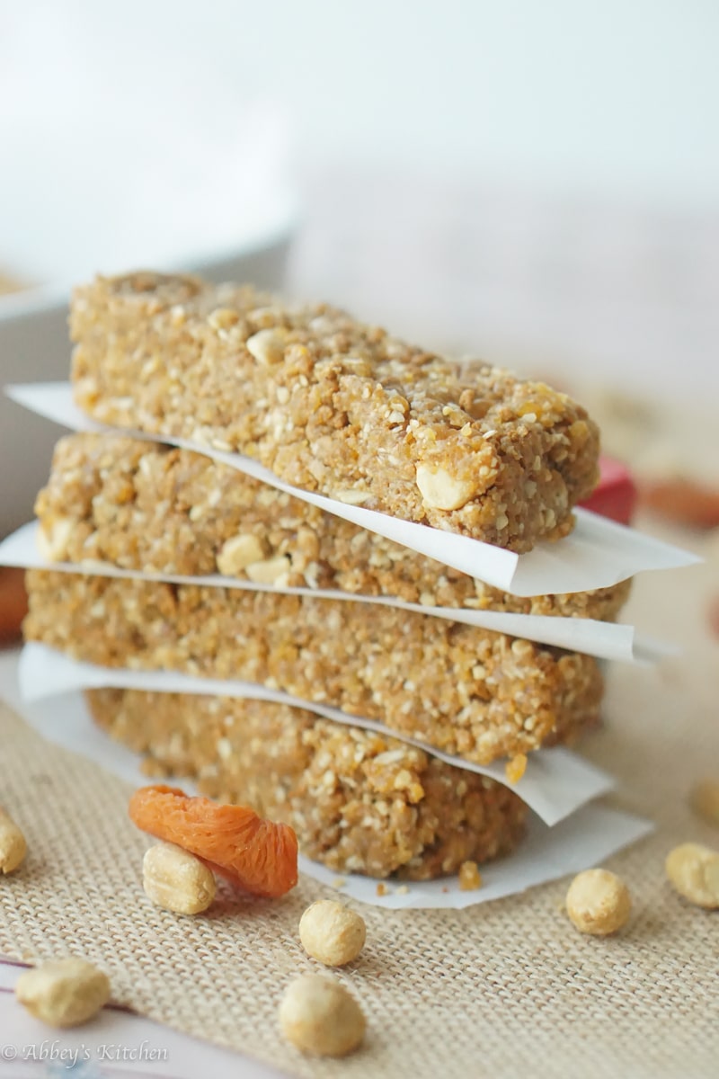 A stack of four gluten free no bake granola bars with peanut butter and apricot with parchment paper in between.