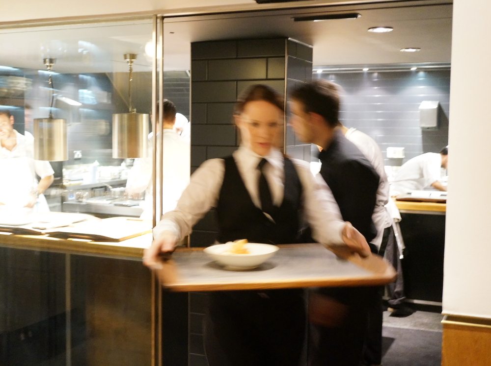 A waiter holding a tray of food in a kitchen.