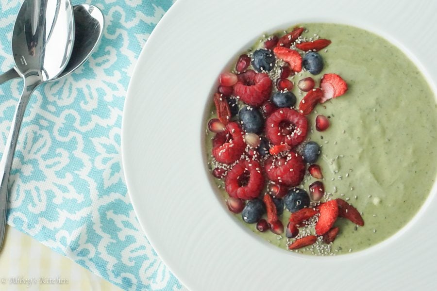 birds eye view of paleo matcha green smoothie bowl topped with berries and chia seeds in a white bowl