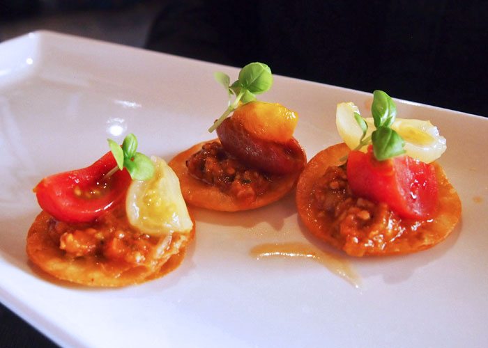 A set of three tomato appetizers on a plate. 